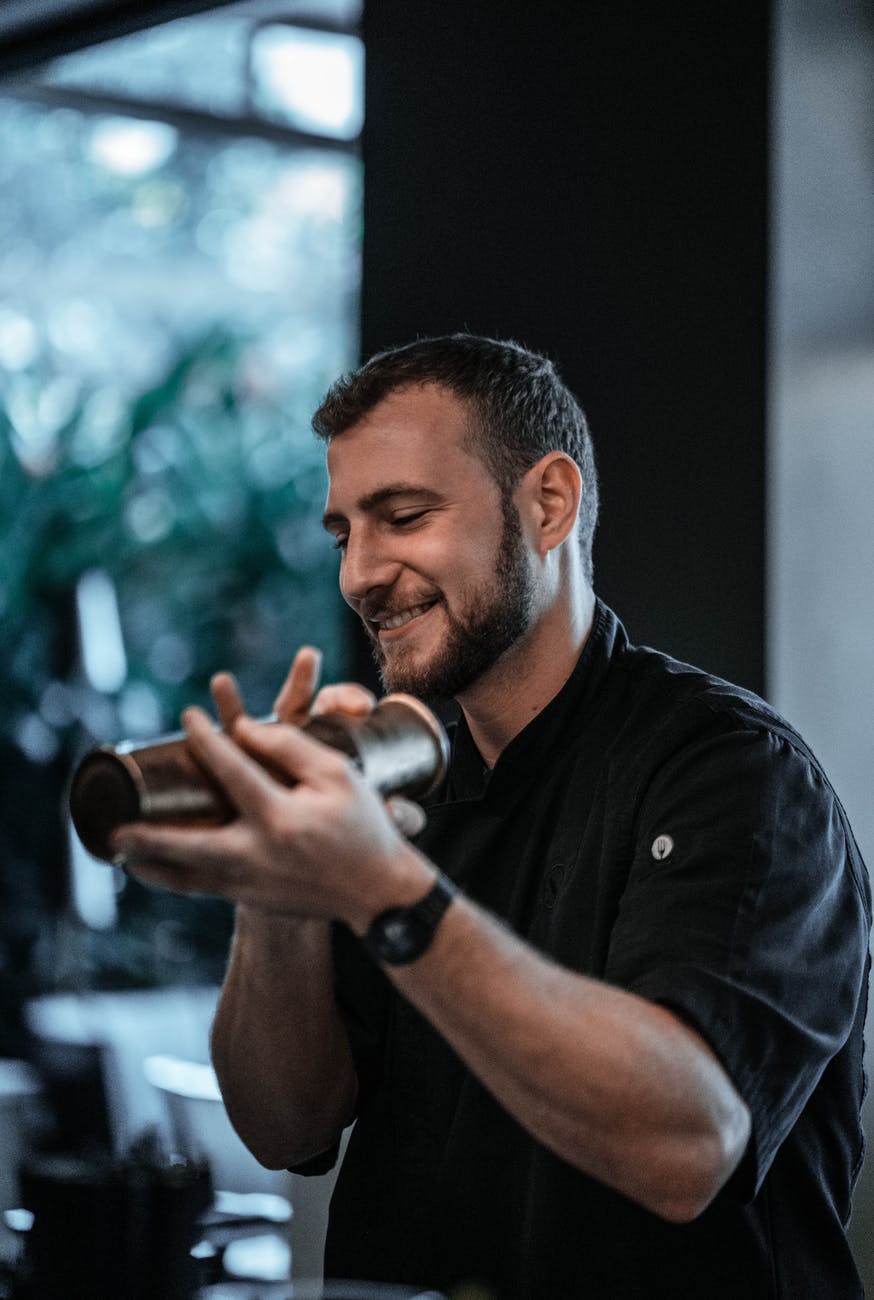 cheerful barman preparing cocktail with shaker