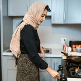 ethnic woman in headscarf switching on stove