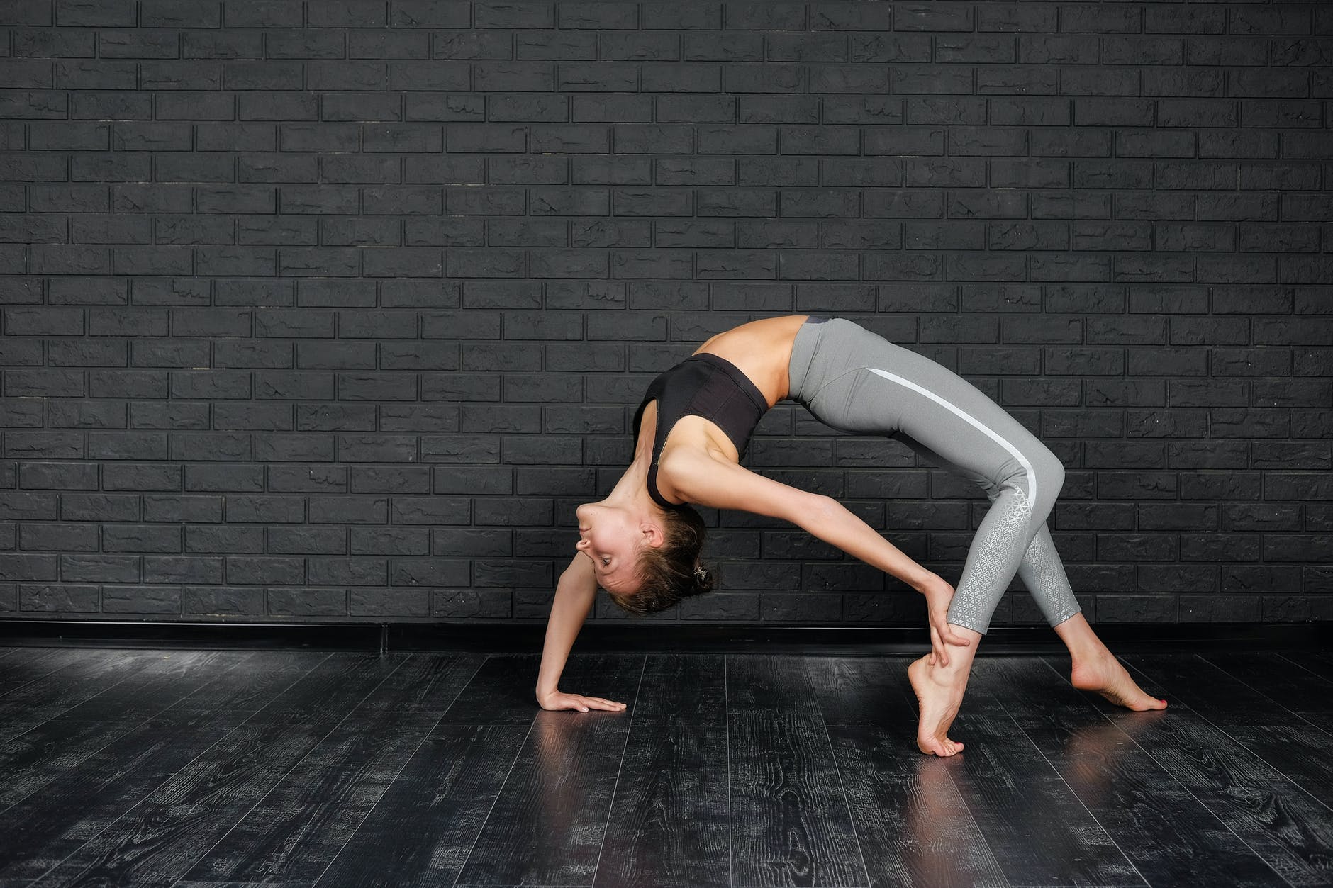 flexible woman practicing urdhva dhanurasana in studio