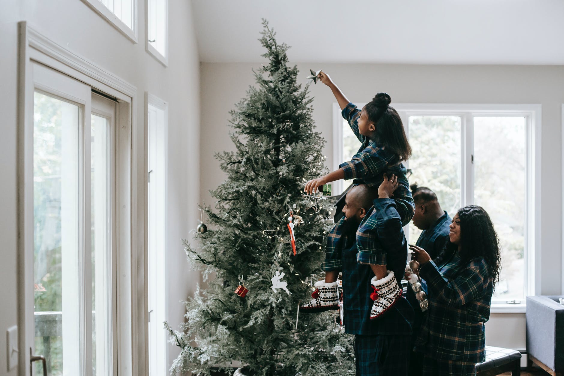 a girl putting a christmas star on a christmas tree