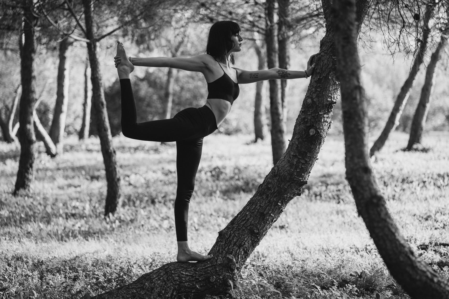 monochrome concentrated lady doing lord of the dance pose in park