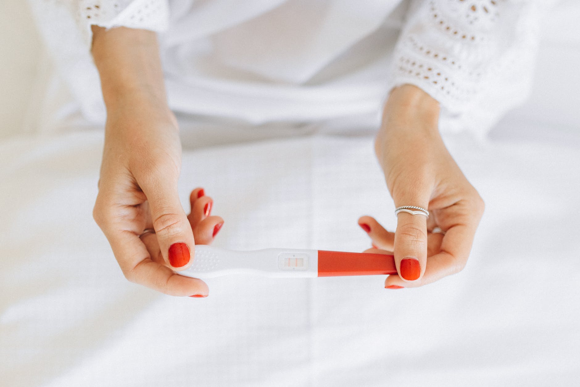 person wearing silver ring holding white and red paper FERTILITY DOESN’T FINISH AT 40